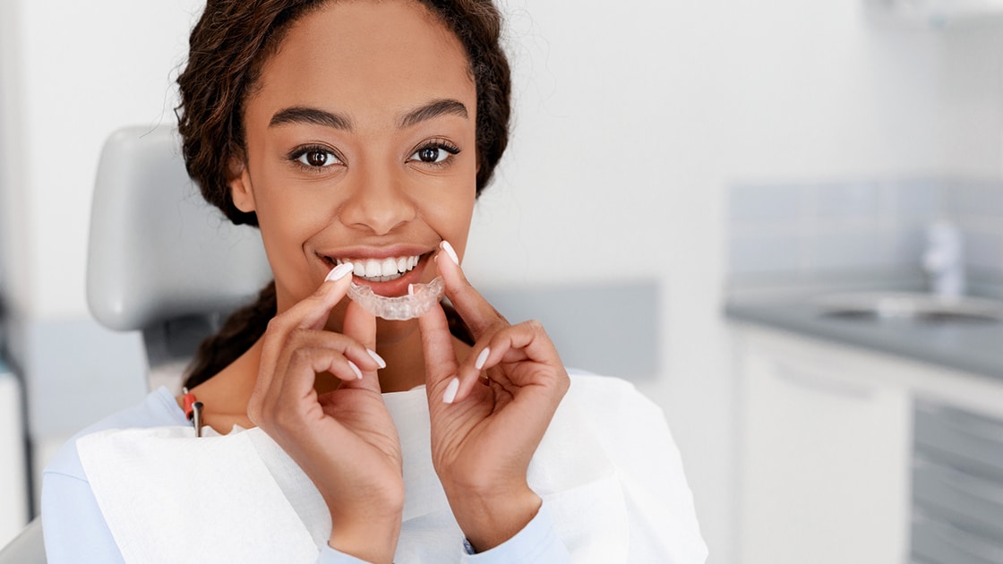 woman in dental chair putting in oral appliance