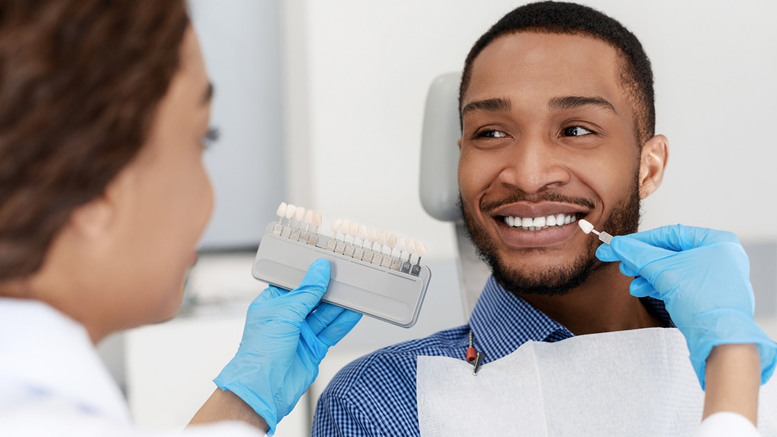 tooth shade guide being held against patient's teeth