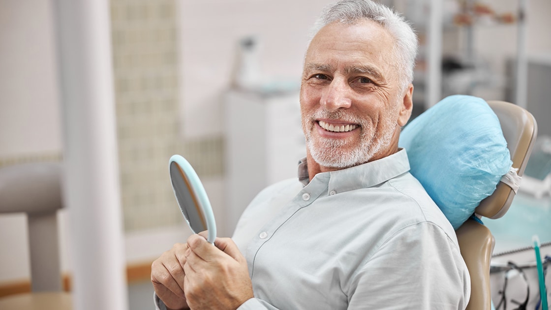 mature man in dental chair smiling
